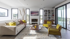 A modern living room with a sofa, armchairs, a coffee table, and a bookshelf. - Casa Baia Estate ★★★★★ (Calvi)