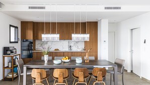 A modern dining area with a large table, wooden chairs, and pendant lights. - Casa Baia Estate ★★★★★ (Calvi)