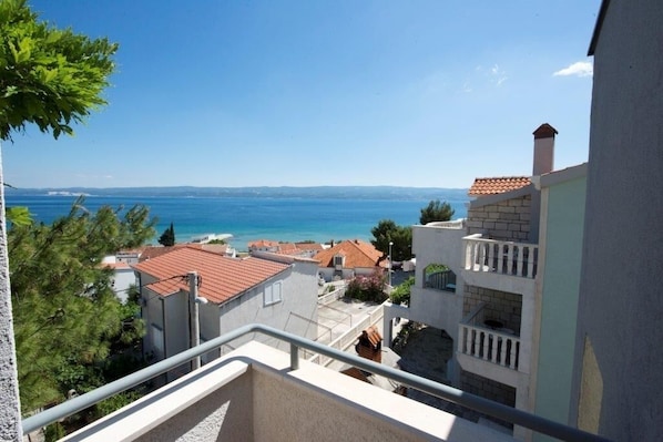 A coastal residential area with buildings, a clear blue sky, and a view of the sea.