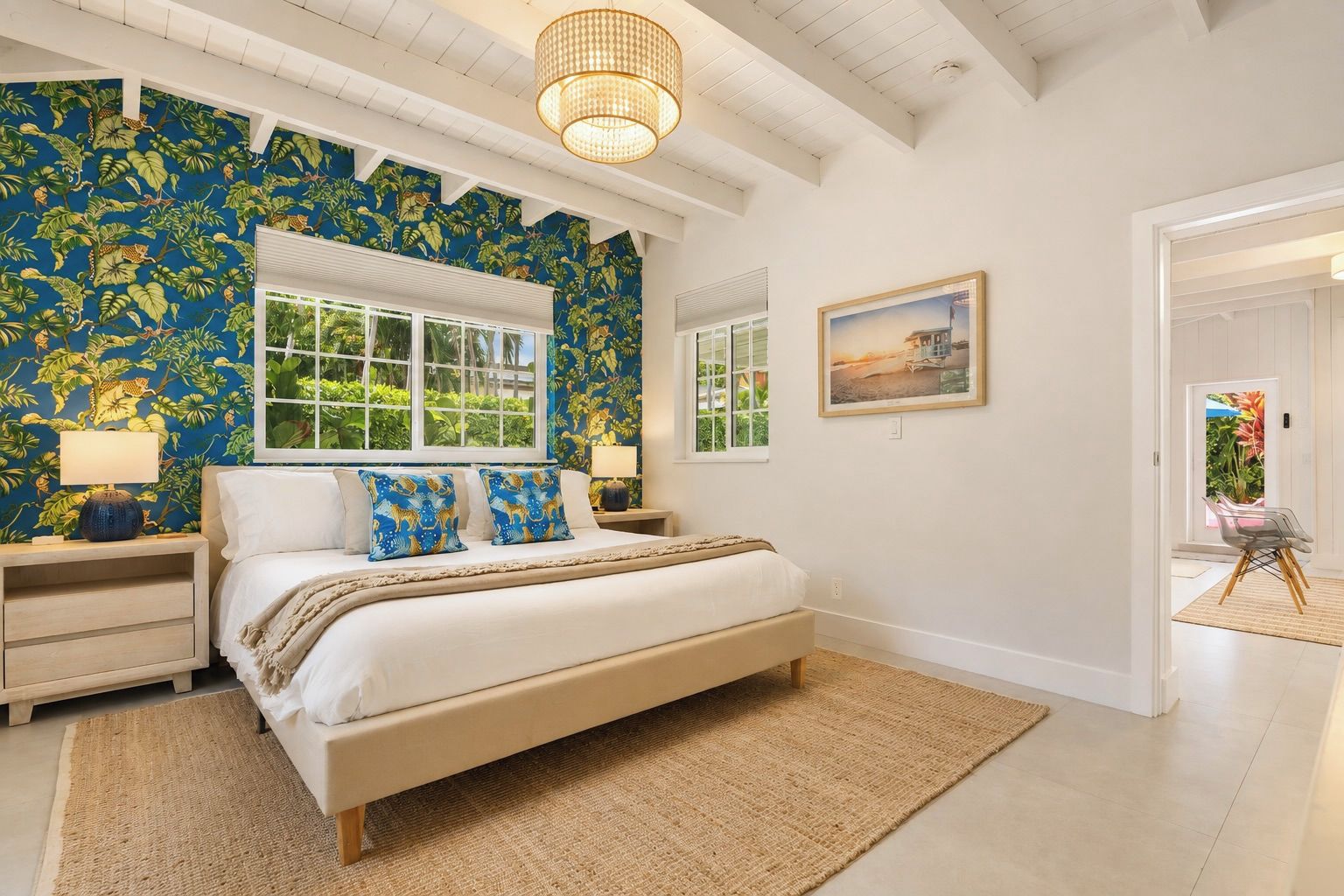 A bedroom with a large bed, two bedside tables, a window, and a tropical wallpaper.