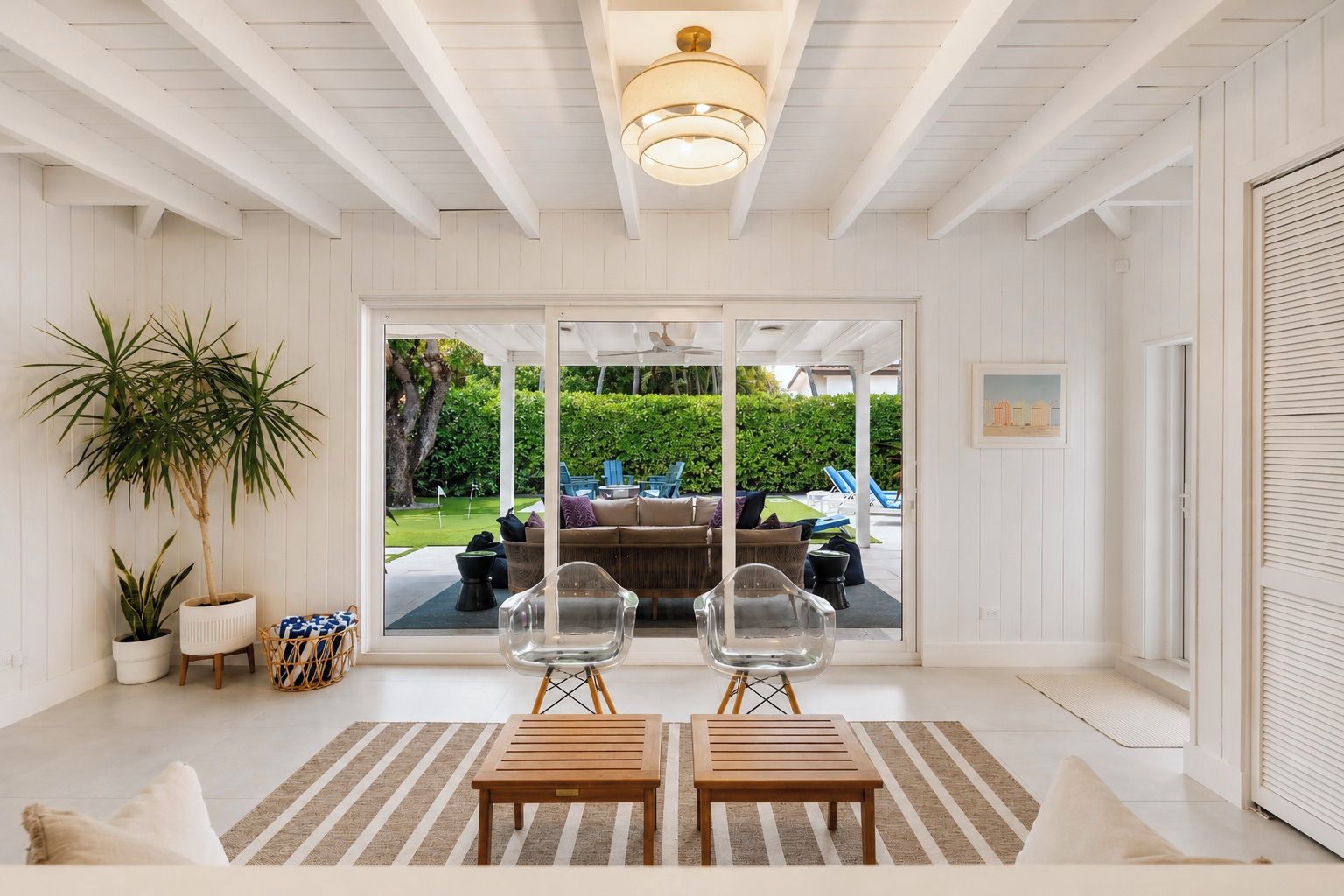 A room with a wooden ceiling, a large window, and a view of an outdoor seating area.