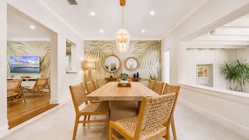 A dining area with a wooden table and wicker chairs, a large mirror, and a view of the outdoors.