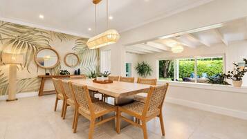 A dining area with a large wooden table, wicker chairs, and a ceiling light fixture.