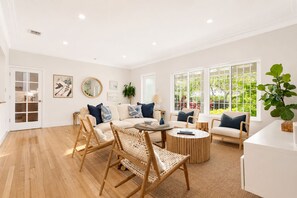 A spacious living room with a sofa, chairs, a coffee table, and large windows offering a view of greenery. - Saltwater Pool, Fire Pit | Gated Brickell Oasis (Miami)