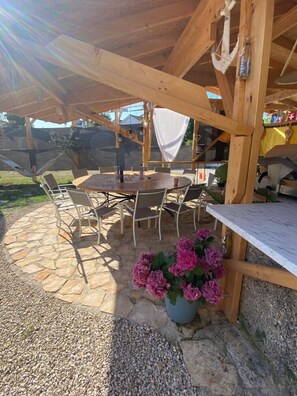 A covered outdoor patio with a stone floor, a round wooden table, and several chairs. - Studio apartment in Funtana with Balcony, Air condition, WIFI, Washing machine (4982-2) (Funtana)