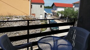En balkon med stenvæg, et bord og to stole.