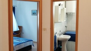 A room with a bed, a chair, a small table, and a bathroom with a sink and mirror. - Apartment in Funtana with Terrace, Air condition, WIFI, Washing machine (4982-7) (Funtana)