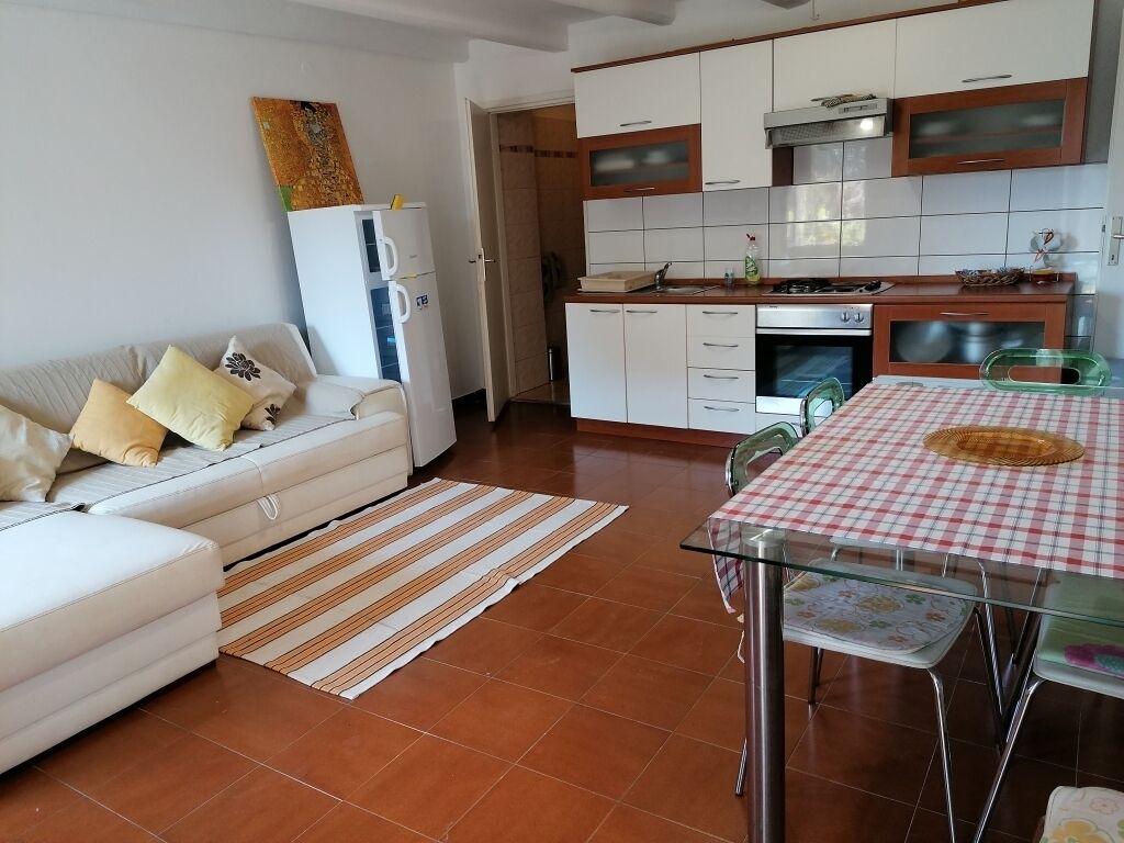 A modern kitchen with white cabinets, a dining table with a checkered tablecloth, and a striped rug.