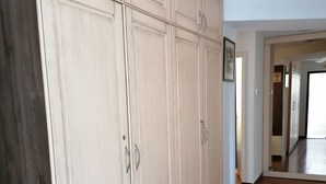 A spacious hallway with a large white wardrobe and a wooden floor.