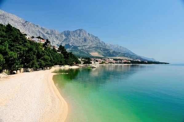 A coastal beach with a clear view of mountains in the background.