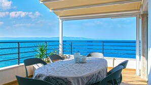 A covered outdoor seating area with a table and chairs, overlooking a body of water with a clear sky. - Apartment in Drašnice with Seaview, Terrace, Air condition, WIFI (4992-3) (Drašnice)