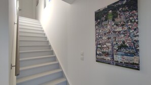 A staircase with white steps leading to a landing, a white wall, and a colorful cityscape painting. - Villa 4 ch - Calme- Plein Sud- SPA (Merlimont)