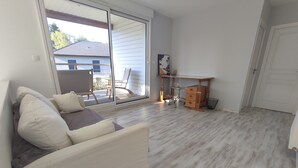 A living room with a sofa, a desk, and a chair. - Villa 4 ch - Calme- Plein Sud- SPA (Merlimont)