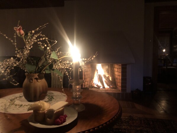 A cozy room with a fireplace, a vase with flowers, and a table with a plate of food.