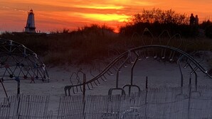 A beach with a lighthouse, a metal fence, and a dune. - Parkview Cottage #7 - 1/2 block to city beach (Ludington)