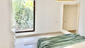 Una camera da letto moderna con un'ampia finestra, un termosifone e una coperta a maglia verde.