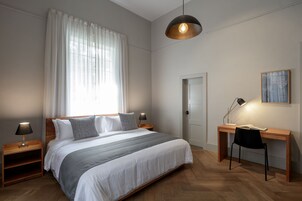 Un dormitorio con cama, mesitas de noche, escritorio y una silla.