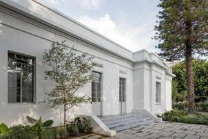Un edificio blanco con grandes ventanales y una escalera que conduce a la entrada.