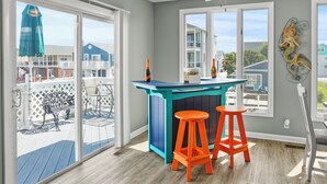 A kitchen with a teal island, two orange stools, and a view of the deck and neighboring houses. - Waterfront 5BR • Dock • BYO Boat • Sleeps 16 • 2 Living Rooms • 2 Miles to Beach (Selbyville)