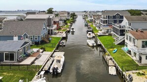 A canal lined with houses, boats docked along the water, and a clear sky. - Waterfront 5BR • Dock • BYO Boat • Sleeps 16 • 2 Living Rooms • 2 Miles to Beach (Selbyville)