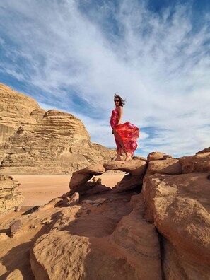 A desert landscape with rocky formations and a person in a red dress.