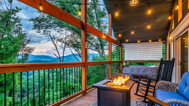 Una terraza de madera con un brasero, asientos al aire libre y vistas al bosque.
