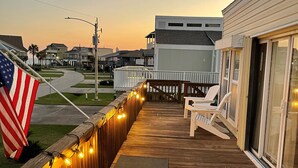 A wooden deck with string lights, a flag, and a bench. - Oceanview Beach House - steps from the beach, really close to Galveston. TipSea! (Galveston)