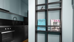Una cocina moderna con armarios negros, suelo de madera y una estantería negra llena de libros.