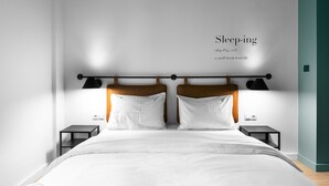 Un dormitorio moderno con una cama grande, dos mesitas de noche y una lámpara de pared.