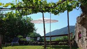 An outdoor seating area with a table and chairs, a solar panel, and a wooden bench. - Country house near sea, ideal for families and all outdoor activities. (Finale Ligure)