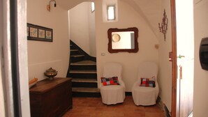 A staircase leading to a second floor, a small window, a mirror, and two chairs with cushions. - Country house near sea, ideal for families and all outdoor activities. (Finale Ligure)