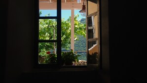 A window with a view of lush greenery and a distant mountain range. - Country house near sea, ideal for families and all outdoor activities. (Finale Ligure)