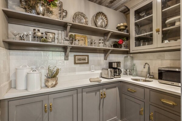 A kitchen with grey cabinets, a coffee maker, a toaster, and decorative items on shelves.