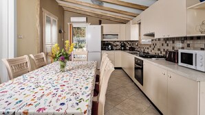 Une cuisine équipée d’une table à manger, de chaises, d’un réfrigérateur, d’une cuisinière et d’un four à micro-ondes.