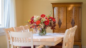 Une table à manger ornée d’un vase de fleurs, entourée de chaises en bois.