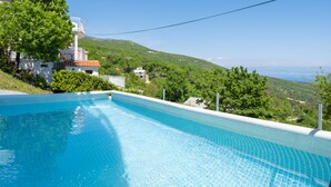 Une piscine offrant une vue dégagée sur une colline et un bâtiment situé au loin.