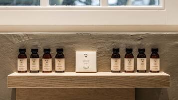 Een houten plank met diverse huidverzorgingsproducten en een bordje met de tekst 'SC H Limestone Memories Soap'.