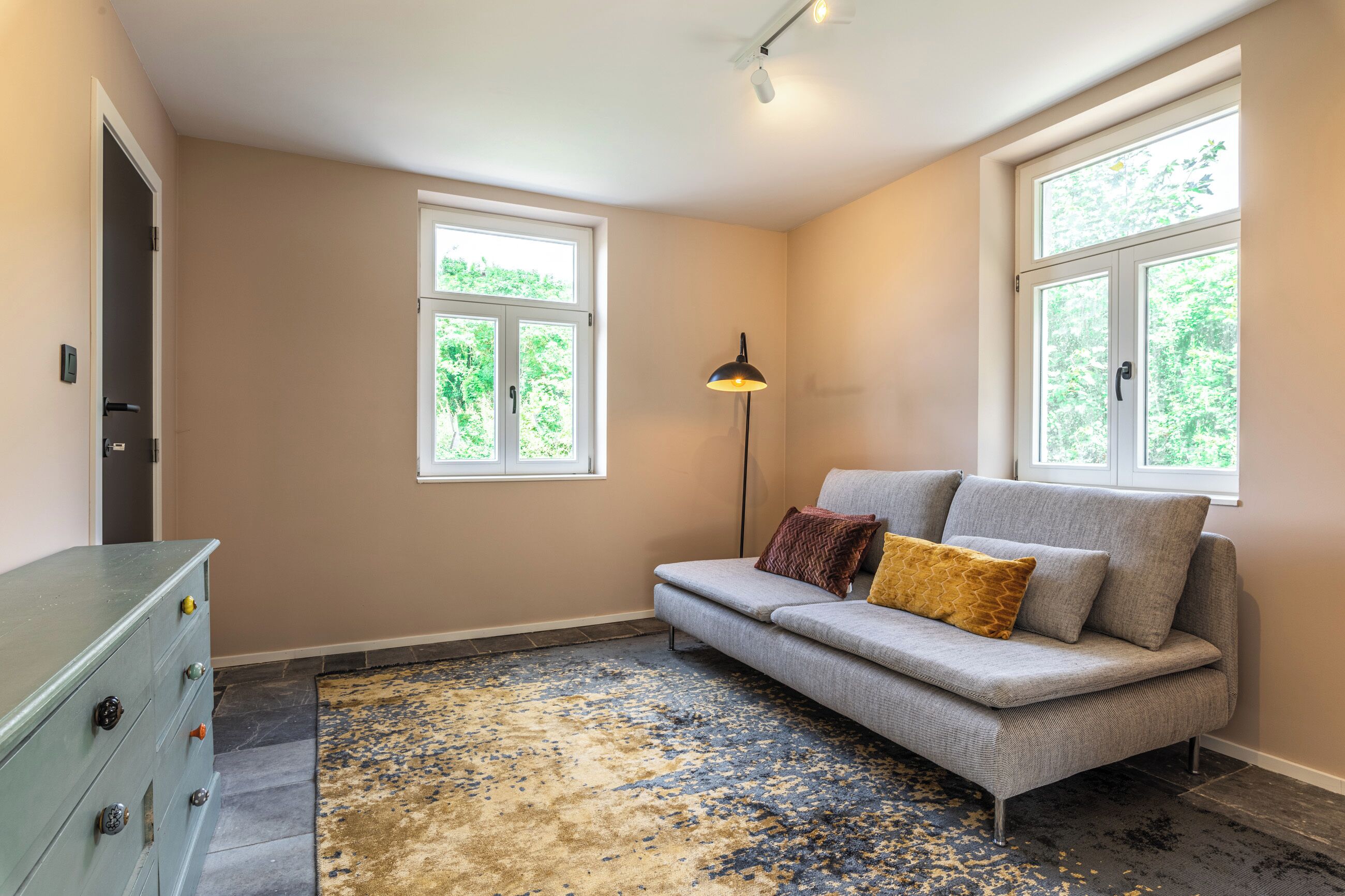 A room with a sofa, a lamp, and a dresser.