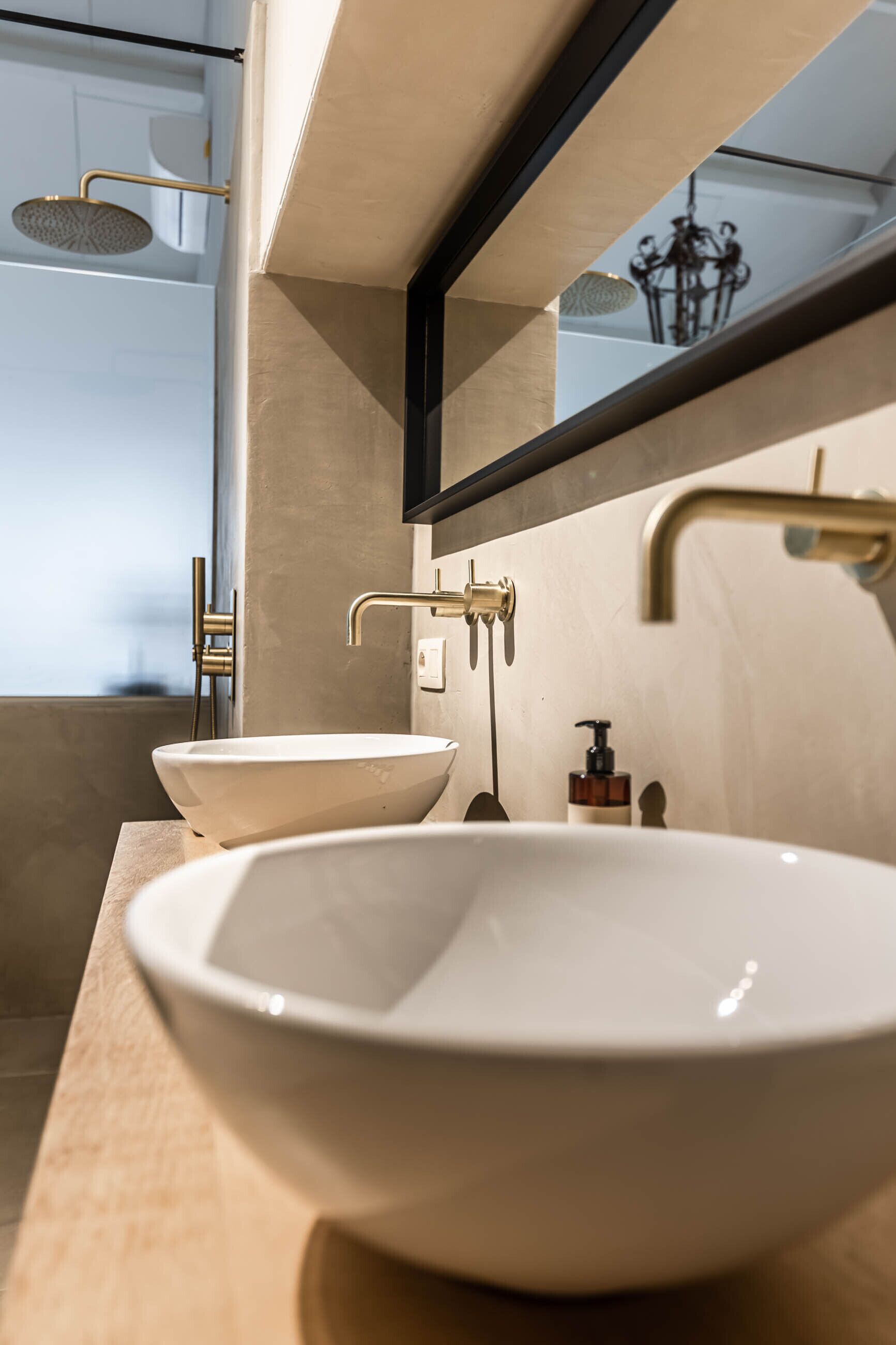 A modern bathroom with a large mirror, two sinks, and a showerhead.