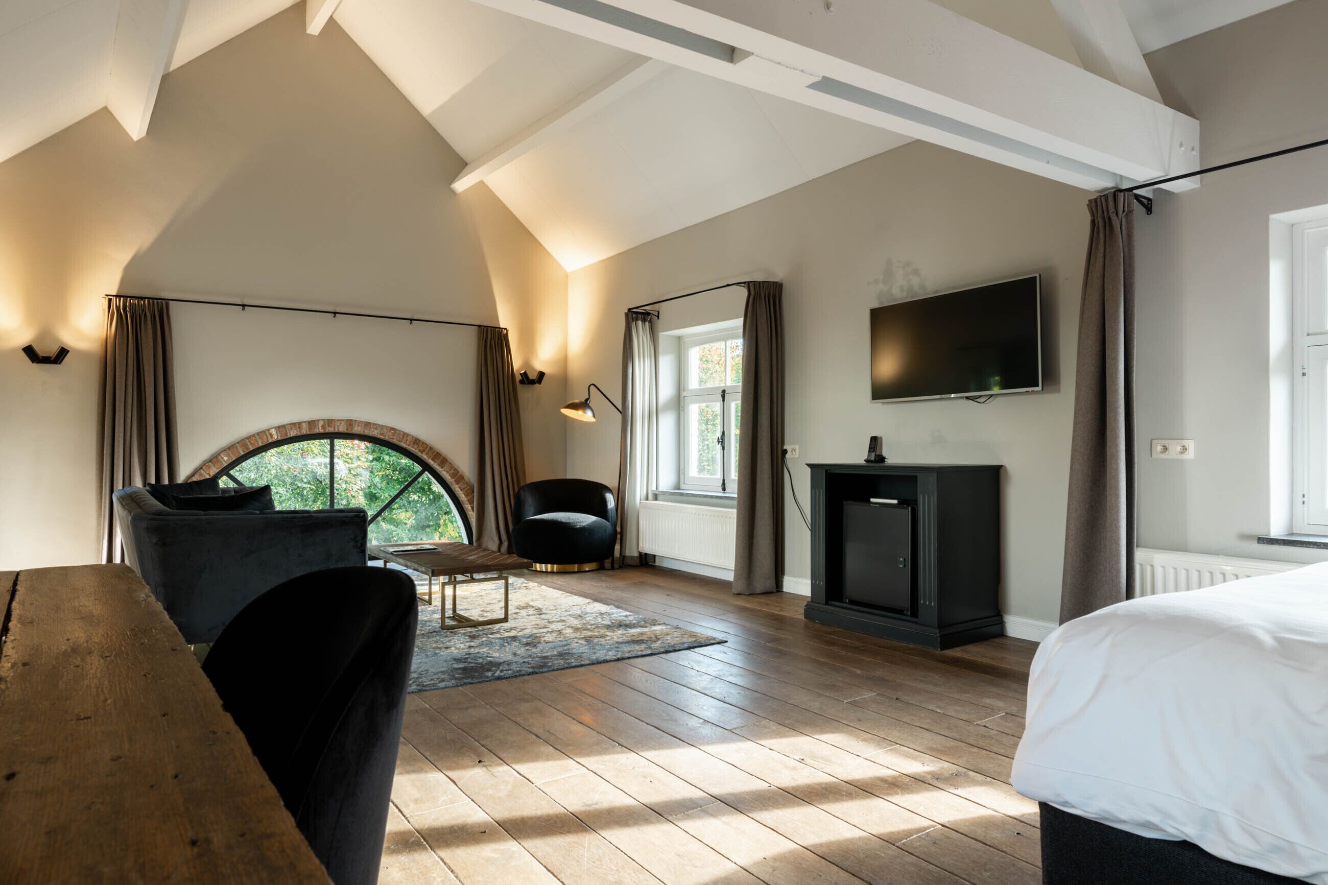 Une chambre spacieuse aménagée en loft, dotée d’une grande fenêtre, d’une cheminée et d’un téléviseur.
