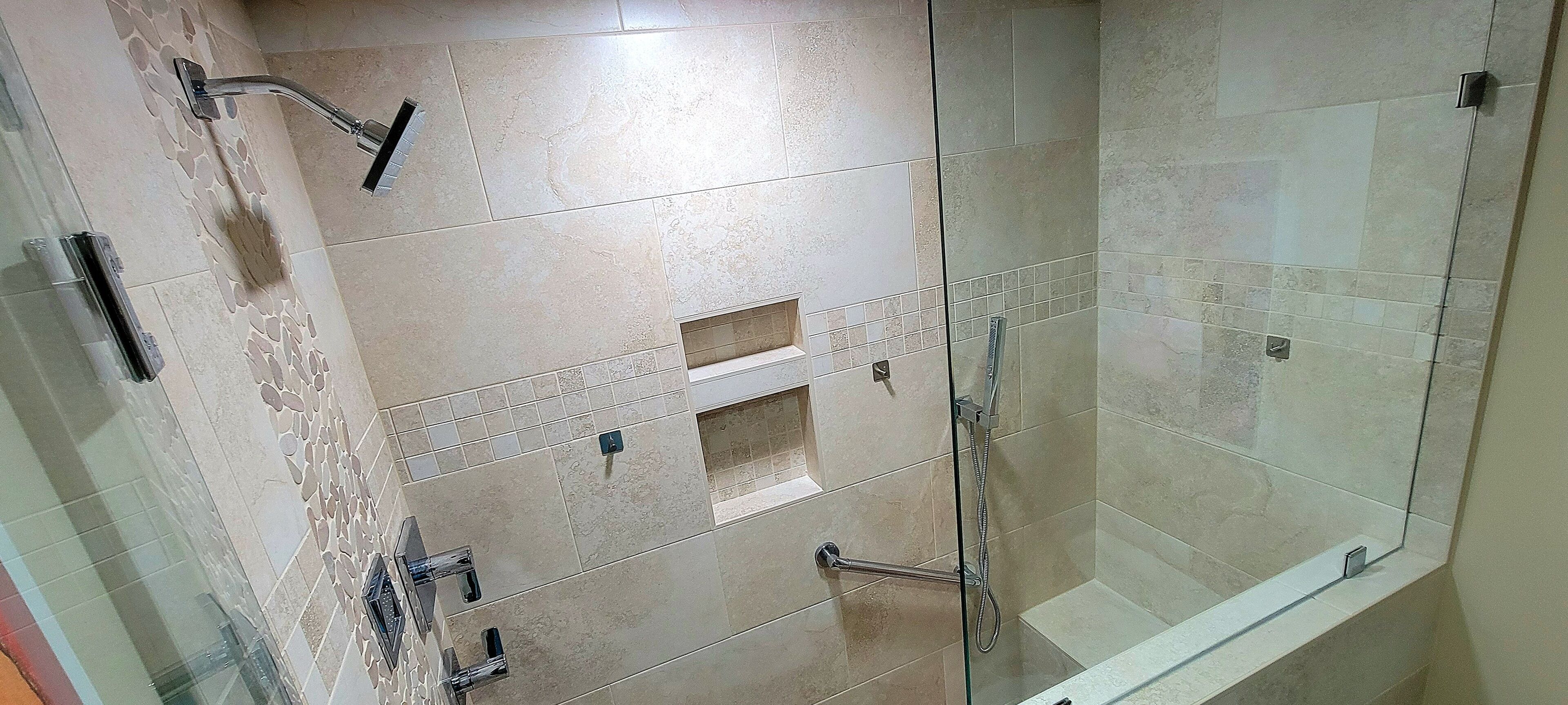 Une salle de bain moderne avec une douche à parois de verre, des carreaux de couleur beige et un banc intégré.