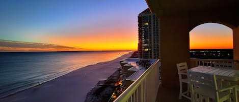 A balcony with a view of the beach at sunset.