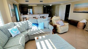 Ein Wohnzimmer mit Ecksofa, Couchtisch und Deckenventilator.