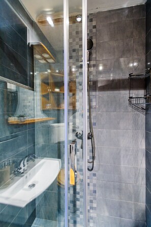 Un baño moderno con ducha envuelta en vidrio, un lavamanos y un espejo.