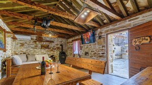 A rustic stone-walled room with a wooden table, benches, and a television. - Ranch Wild North (Benkovac)