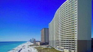 Un hotel sulla spiaggia con diversi piani, vista mare e cielo azzurro.