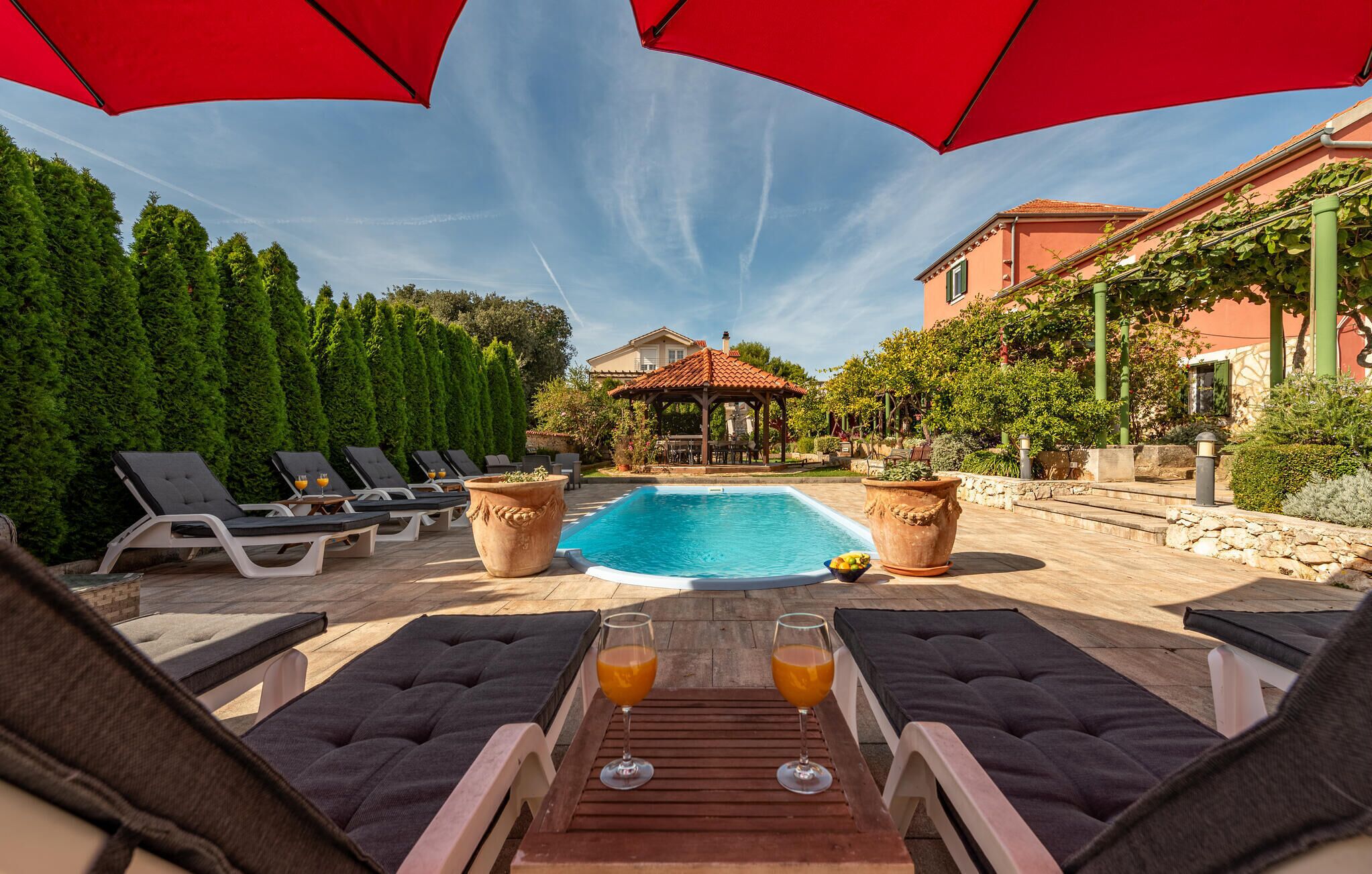 A pool area with lounge chairs and a gazebo.