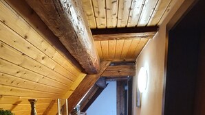 Un pasillo estrecho con paredes de madera y techo inclinado, que lleva a una puerta al final.