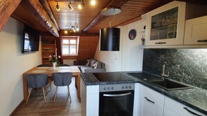 Una cocina compacta con horno integrado, un lavamanos y vigas de madera en el techo.