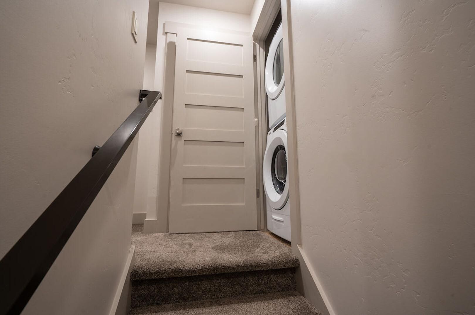 Una estrecha escalera con barandilla que lleva a una puerta.